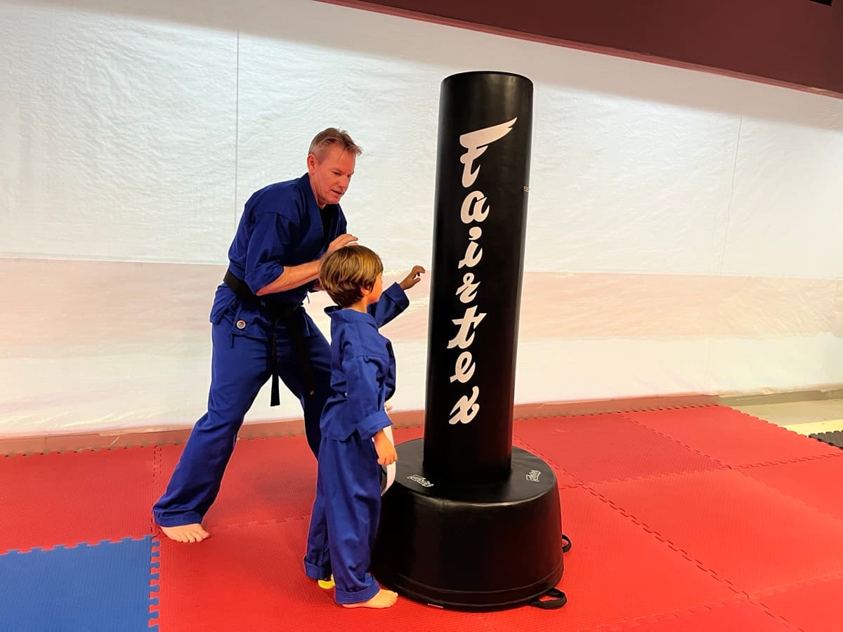 A Guide coaching a young ninja at the kick bag